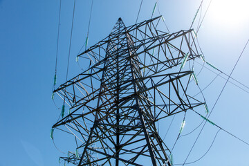 A tall power tower with wires and a blue sky in the background