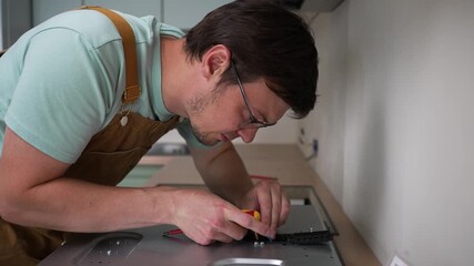 Professional electrician carefully connecting electrical wires to new stainless steel electric stove during precise kitchen appliance installation process