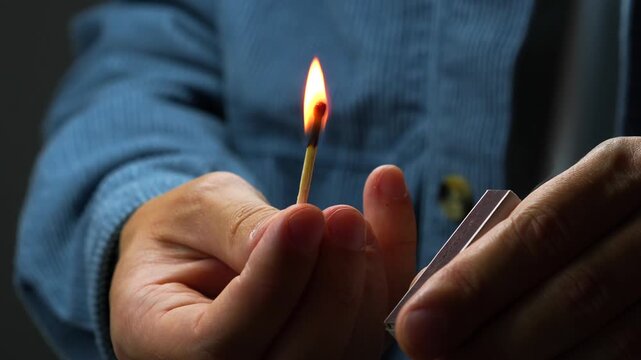 A man's hand lights a match on a matchbox close-up.
Wooden match and corton matchbox.
Ignition of a wooden match.
Flammable items
