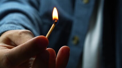 A man in a blue shirt lights a match close-up.
A burning wooden match and a corton matchbox.
Burning fire in the guy's hands - Powered by Adobe