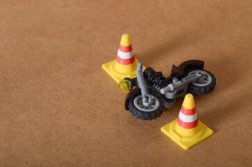Mini Traffic Cone and Toy Motorcycle Depicting Road Safety Accident Simulation on Brown Background