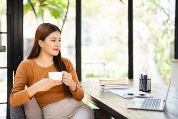 Young smiling businesswoman on coffee break in home office.