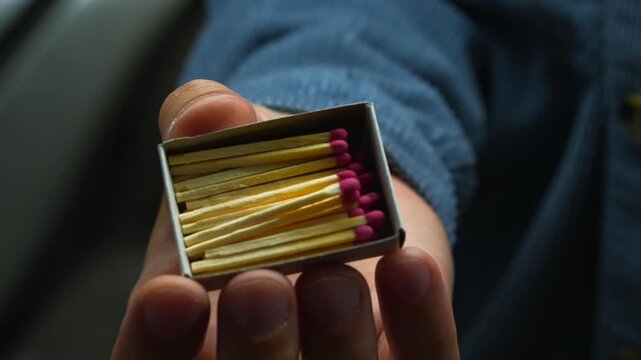 A matchbox with matches in the hands of a man in a blue shirt close-up