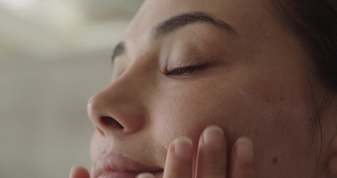 Young woman applying cream to her face