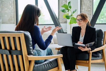 Female journalist, employer interviewing working with woman sitting together in office