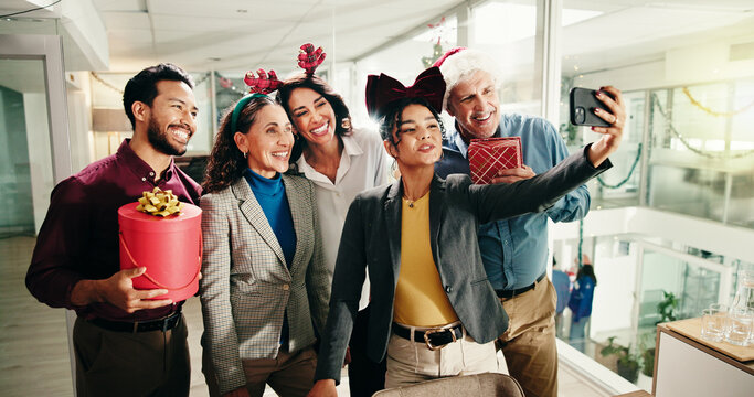 Christmas, business people and team selfie in office for photography with gift. Xmas picture, friends and happy workers with holiday spirit, December celebration or memory for social media at party