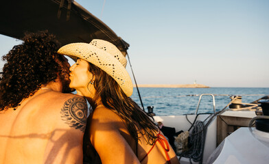 Romantic couple enjoying a leisurely summer day, kissing on a sailboat during their vacation