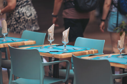 Dining in an outdoor café with vibrant blue tables and elegant glassware, creating a lively atmosphere in early afternoon - Powered by Adobe