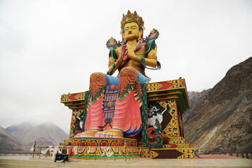 Outdoor large statue of Maitreya Buddha near Diskit Monastery in Nubra valley on white sky background at Jammu and Kashmir, India.