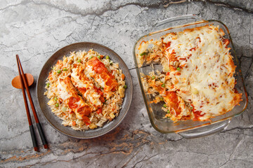Baked Pork Chop Rice consists of a base of fried rice with egg, which is topped with tomato sauce and cheese closeup in a plate on the table. horizontal top view from above