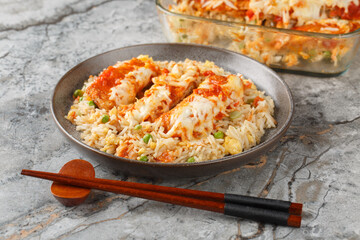 Baked Pork Chop Rice is a Hong Kong classic dish egg fried rice, seared pork and a rich tomato sauce rest under cheese closeup in a plate on the table. horizontal