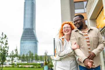 Couple enjoying a joyful moment outdoors near a modern building with a tall tower in the background...