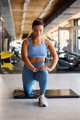 Female athlete doing stretching exercises during gym workout.