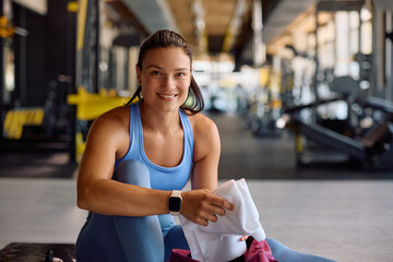 Happy sportswoman taking towel from her gym bag and looking at camera.