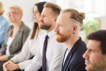 A group of diverse professionals attentively listens and participates in a workshop held in a...