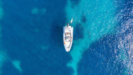 Plan de vue aérien sur un bateau en plein milieu de la mer Méditerranée vers des falaises avec une eau bleue et turquoise  