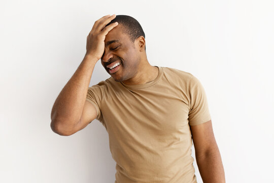 Upset black man with hand on forehead, reacting to problem or silly moment. African american male expressing oops or embarrassment in casual style, copy space