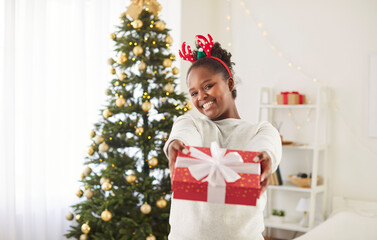 Merry Christmas and Happy New Year holiday african american woman presenting new year gift box glad...