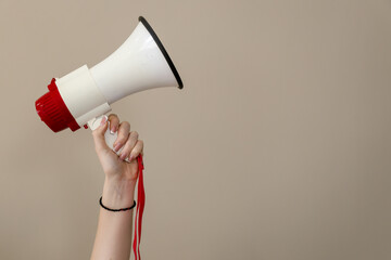 Hand holding megaphone against neutral background