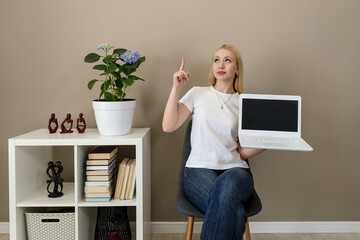 Woman holding laptop with blank screen and pointing up with idea expression