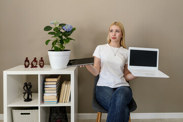 Woman comparing tablet and laptop with unsure expression