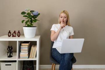 Woman making shushing gesture while working on laptop at home