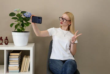 Woman taking selfie and showing peace sign in cozy home setting