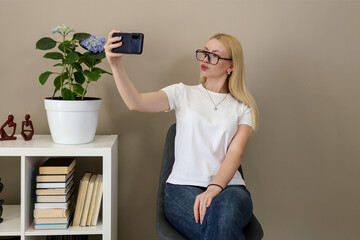 Woman taking selfie with smartphone at home in casual setting
