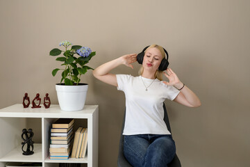 Playful woman dancing in headphones while sitting at home