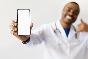 Closeup of doctors hand showing blank phone screen at camera. Modern health app or telehealth promotion with mockup device in medical context, white background