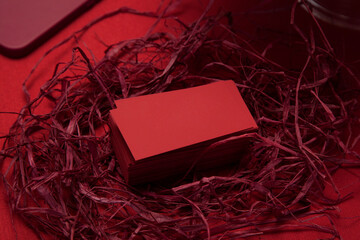 Blank red business cards in decorative nest of red raffia