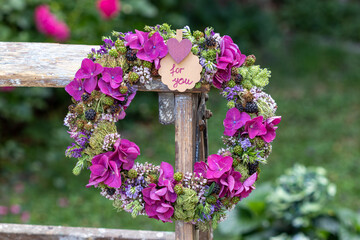 Blumenkranz mit Hortensienblüten, Wilder Möhre, Feldthymian, Luzerne und Brombeeren hängend auf einer Leiter