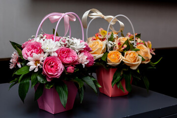 Beautiful mixed flower bouquets with roses, daisies and greenery in pastel paper baskets with ribbon handles, perfect for celebrations or gifts