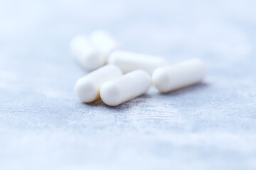 Creatine capsules on bright wooden background. Soft focus. Close up. Copy space.	