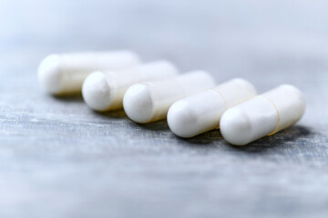 Beta-alanine capsules. Bodybuilding food supplements on wooden background. Soft focus. Close up....