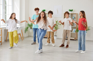 Group of happy preteen friends having fun together, supporting their female classmate dancing in...