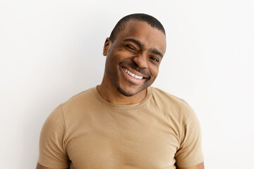 Closeup portrait of cheerful man winking and smiling playfully. Expressive face with charm and...