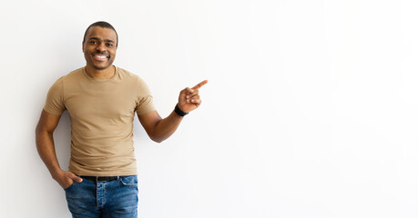 Smiling man in tshirt pointing aside at copy space with hand. Friendly and confident gesture...