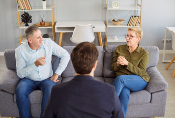 Serious elderly family couple attending a therapy session, engaging in conversation with a...