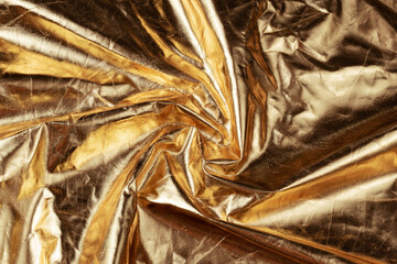 Golden background texture. Golden colored wavy fabric.