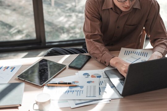 Business Professional Analyzing Data on Laptop Surrounded by Charts