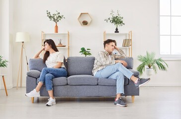 Family couple sits on the couch at home, feeling offended and sad after a quarrel. Emotional impact...