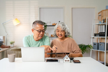 Happy senior couple reading important documents while sitting together at the table at home....