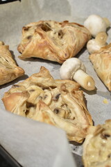 puff pastry with mushrooms decorated by raw champignons, top view