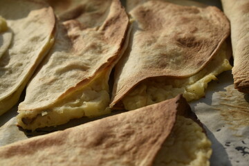 close-up baked burritos and stuffed tortillas on baking sheet, top view 