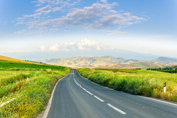 beautiful landscape of long road to amazing mountain scene from a green summer fields and hills....