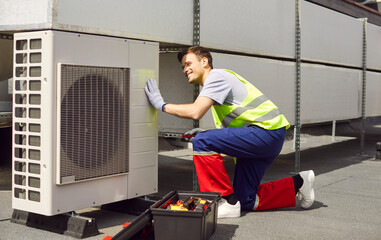 Worker or engineer conducts maintenance and repair of an air conditioning HVAC system on a roof....