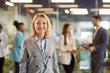 Portrait of young smiling blonde professional company employee in meeting room. Confident satisfied...