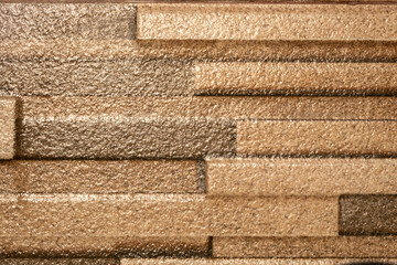 Close-up of textured golden brown stone wall tiles with a rough surface and layered horizontal pattern, ideal for backgrounds, interior design, or architectural materials.