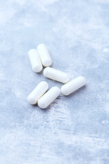 Creatine capsules on bright wooden background. Soft focus. Close up. Copy space.